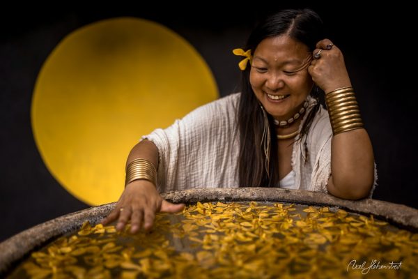 A joyful woman interacts with floating yellow petals in a serene, circular backdrop, evoking a tranquil atmosphere.