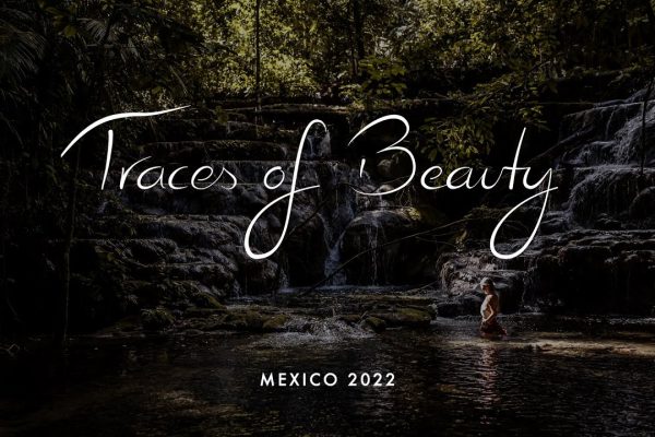 A serene waterfall in a lush forest with a person exploring the water, showcasing nature's beauty in Mexico 2022.