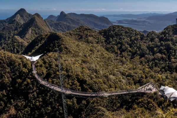 A breathtaking aerial view of the Langkawi Sky Bridge surrounded by lush mountains and a clear blue sky.